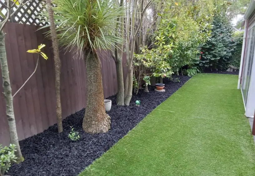 Garden bed with black mulch and fake grass